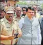  ?? PTI PHOTOS ?? (From top) People watch as the helicopter carrying Maharashtr­a chief minister Devendra Fadnavis makes an emergency landing in Latur on Thursday; (left) the wreckage of the chopper and Fadnavis being escorted by policemen after the incident.