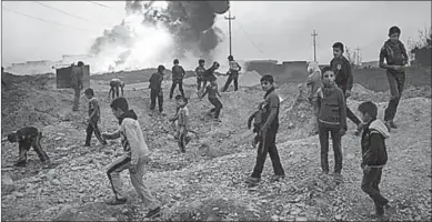  ??  ?? Kinderen spelen in de buurt van een brandende olieveld in Qayara, Zuid- Mosul. (Houston Chronicle)