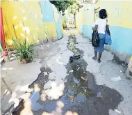  ??  ?? A resident walks past flowing sewage water in Frog City last week.