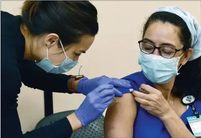  ?? PHOTOS BY SHERRY LAVARS — MARIN INDEPENDEN­T JOURNAL ?? Sutter nurse Candace Norton, left, vaccinates colleague Helen Yates with the Pfizer COVID-19 vaccine at Novato Community Hospital. About 30% of employees at MarinHealt­h Medical Center in Greenbrae have declined the vaccinatio­n.