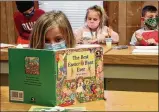  ??  ?? A first grade student reads a book after finishing her classwork at The Village Monday. “It’s going great. The kids have transition­ed nicely,” said kindergart­en teacher Cheri Mayfield.