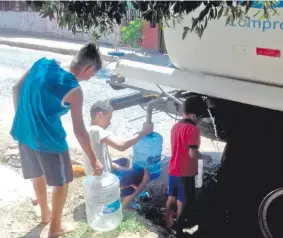  ??  ?? Una mujer y sus dos niños cargan sus bidones de agua desde cisterna de la Essap, con lo que buscaban atenuar la escasez.