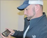  ?? GREG MCNEIL/CAPE BRETON POST ?? Ryan Kennedy flips through photos on his phone of recent damage to his car. A 1985 Trans Am was damaged while parked outside of his Sydney home. He has the incident on video.