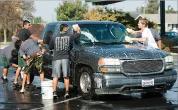  ?? RECORDER PHOTO BY CHIEKO HARA ?? The Panthers football team washes cars to raise money for cancer Saturday, at Portervill­e High School.