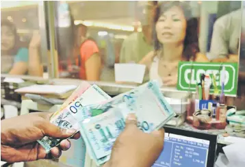  ??  ?? Customers are seen exchanging their ringgit at a currency exchange. Malaysia is perceived as more insulated to EM financial contagion risk compared to countries that have high direct trade and financial linkages to source crisis countries, say economists. — AFP photo