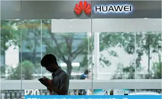  ??  ?? BEIJING: A man uses his mobile phone outside a Huawei store in Beijing. —AFP