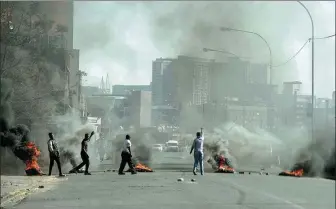  ?? LUCA SOLA / AFP ?? Protesters burn tires in Jeppestown, Johannesbu­rg, on Monday, as the unrest spreads to South Africa’s commercial hub.