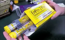  ?? Rich Pedroncell­i/Associated Press ?? A pharmacist holds a package of EpiPens epinephrin­e auto-injector, a Mylan product, in Sacramento, Calif.