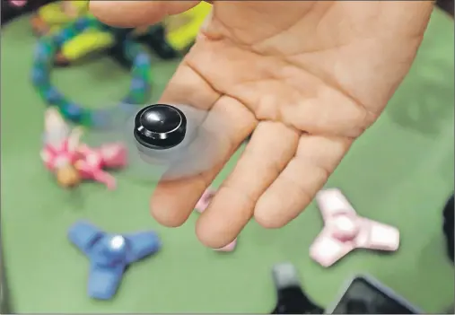  ?? AP PHOTO/CARLOS OSORIO ?? Funky Monkey Toys store owner Tom Jones plays with a fidget spinner in Oxford, Mich.