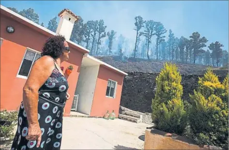  ?? BORJA SUAREZ / REUTERS ?? Una vecina de Fuencalien­te contempla la zona devastada por las llamas junto a su casa