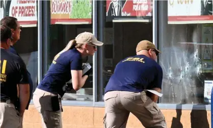  ?? Photograph: Usman Ukalizai/AFP/Getty Images ?? FBI agents look at bullet impacts in a Tops grocery store window in Buffalo, New York, on 15 May, the day after a gunman shot dead 10 people