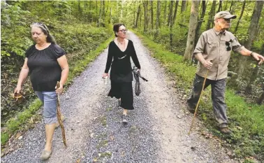  ?? STAFF PHOTO BY DAN HENRY ?? Kris Sherrill, Stephanie Everett and Jay Clark walk along wetlands on Everett’s family property where she is fighting to keep North Georgia EMC from clearing the land to install taller power poles.