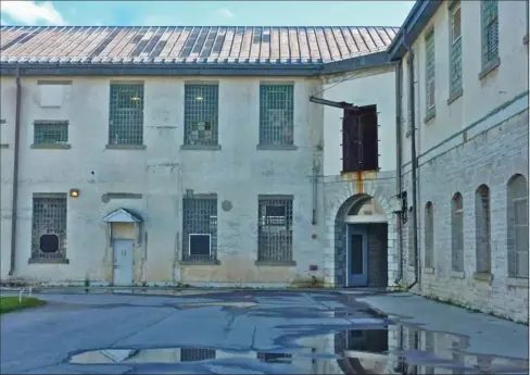  ??  ?? Walls and windows of a building within the walls of the Pen reflected in a courtyard puddle. Below, confiscate­d shivs and shanks displayed at the Correction­al Service museum.