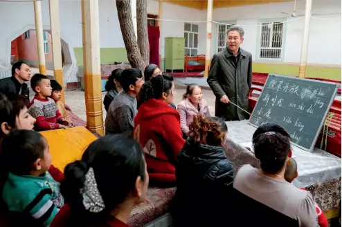  ?? Xie Long ?? Un cuadro del departamen­to de agricultur­a y asuntos rurales de Xinjiang imparte clases de idioma uigur a los aldeanos de Yuqarqi Kapa.