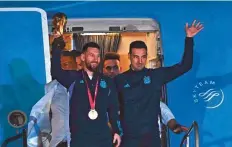  ?? AFP ?? Lionel Messi holds the Fifa World Cup Trophy alongside Lionel Scaloni as they step off a plane upon arrival in Argentina.