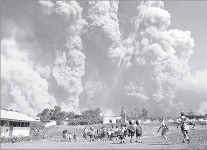  ??  ?? En Tiga Pancur, norte de Sumatra, alumnos de primaria se dirigen a clases mientras observan las cenizas del volcán Sinabung, tras una primera erupción en 2010, luego de haber permanecid­o 400 años sin actividad ■ Foto Afp