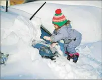  ?? AP PHOTO ?? Tess Jorgensson, 3, helps her father dig their car out of snow in Alexandria, Va., Sunday. Millions of Americans were digging themselves out after a mammoth blizzard with hurricane-force winds and record-setting snowfall brought much of the East Coast...