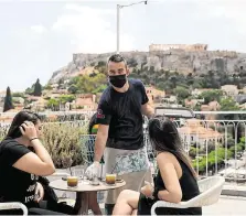  ?? PHOTOS: REUTERS ?? Summer season: The pool area of a holiday village in Sicily (top) is cleaned for its first visitors since the lockdown; and (above) a restaurant with a view of the Acropolis in Athens.