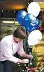  ?? (NewsTimes file) ?? Rexayn Tribble, owner of All About Flowers, ties up Shop Small balloons in front of the flower shop for Small Business Saturday last November.