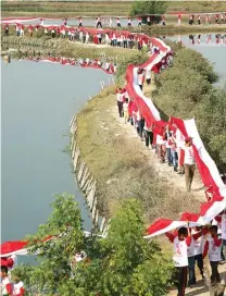  ?? CHUSNUL CAHYADI/JAWA POS ?? SWADAYA: Bendera sepanjang 400 meter yang diarak masyarakat Dusun Thoman, Desa Banjarsari, Manyar, saat jalan sehat kemarin.