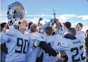  ?? ROBERTO E. ROSALES/JOURNAL ?? La Cueva players celebrate with the state championsh­ip trophy after the Bears defeated Cleveland 33-14 for the large-school state football championsh­ip on Saturday.