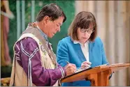  ?? JASON KOSKI/CORNELL UNIVERSITY VIA AP ?? Ray Halbritter, left, representi­ng the Oneida Indian Nation, and Cornell University President Martha E. Pollack sign documents that repatriate ancestral remains from the university to the Oneida Indian Nation during a ceremony Tuesday in Sage Chapel in Ithaca, N.Y.