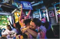  ?? MERIDITH KOHUT/ THE NEW YORK TIMES ?? Laura Rodríguez and Ariana Lyons embrace as they watch President-elect Joe Biden give his victory speech on a television in Atlanta on Saturday. Biden thanked Black voters in his victory speech, saying “you’ve always had my back, and I’ll have yours.”