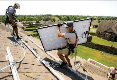  ?? NWA Democrat-Gazette/CHARLIE KAIJO ?? Jarren Stinson (center) carries a solar panel Friday at a home in Centerton. More and more people around Northwest Arkansas and the rest of the state are installing solar panels to generate electricit­y. Caleb Gorden, president of Shine Solar, has installed around 800 panels in Northwest Arkansas and Southwest Missouri. They cost around $10,000 but the company provides financing so homeowners can make payments on the panels.