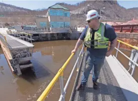  ??  ?? Site safety officer Dan Burger stands on the lock gates as they swing open for a northbound towboat on the Mississipp­i River. Maintenanc­e is behind schedule on river infrastruc­ture.