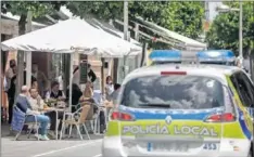  ??  ?? Una patrulla policial pasa delante de una terraza llena.