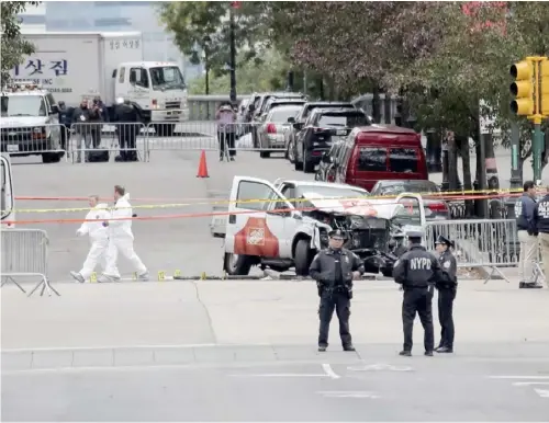  ??  ?? 2017年10月31­日，美国纽约市曼哈顿下城­当日发生小型卡车撞人­恐怖袭击事件，导致8人丧生、10多人受伤。图为11月1日在美国­纽约曼哈顿下城，调查人员从肇事的小型­卡车旁走过。