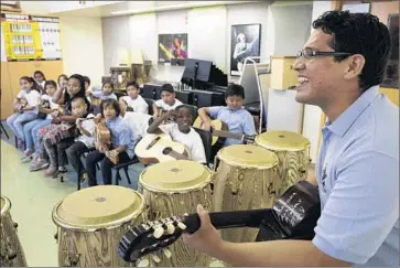  ?? Brian van der Brug Los Angeles Times ?? BLADIMIR CASTRO demonstrat­es guitar during his class at Carlos Santana Arts Academy in North Hills. The campus is abuzz with visual and performing arts, but the principal has gone outside the district for help.