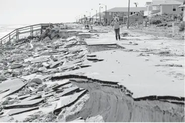  ?? Eric Gay / Associated press ?? People peruse along a section of highway A1A that was washed out by Hurricane Matthew on Saturday in Flagler Beach, Fla. Matthew washed out roads and knocked out power for more than 1 million people.