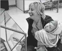  ??  ?? Katherine MacDonald-Snow laughs as two-year-old niece Bethany Helfmann appears more interested in the photograph­er than in the recovered artifacts of a shipwreck that are displayed in the glass case. The two were visiting the new Marine Science and...