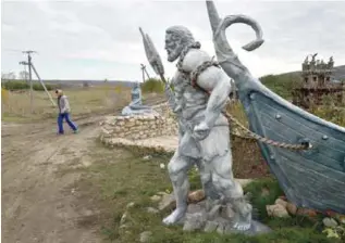  ?? — AFP ?? RUSESTII NOI, Moldova: A woman walks past a plaster statue of a Viking figure in this village on Oct 24, 2016.