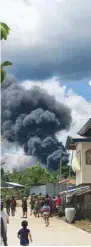  ??  ?? Residents gather as smoke rises from the wreckage after the transport plane crashed on landing in Jolo, Sulu, Philippine­s.