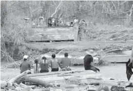  ??  ?? Aftermath of Hurricane Maria: People sit on both sides of a destroyed bridge that crossed over the San Lorenzo de Morovis River in Puerto Rico on Wednesday. New York state is committing aid and hundreds of workers to help.