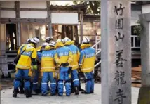  ?? ?? Japanese police officers huddle up before attempting to enter a building to search for earthquake victims on Saturday.