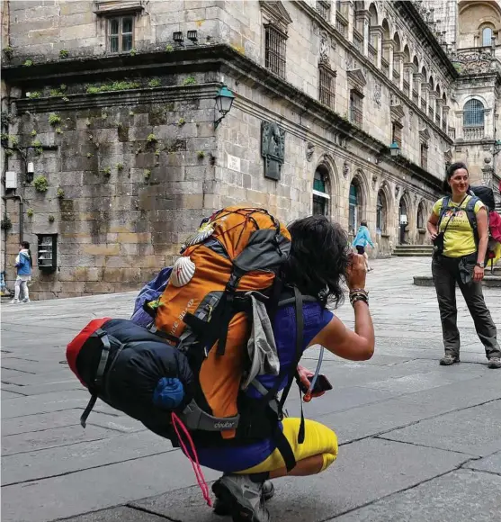  ??  ?? Hikers, called pilgrims, celebrate the end of their journey after walking hundreds of miles on El Camino de Santiago.