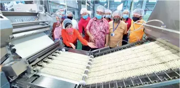  ??  ?? susan (left) and the usCCakk committee, accompanie­d by Chua (second left), watch as the noodles travel into the steamer.