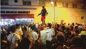  ?? DANIEL A. VARELA AP ?? A man stands on a car as crowds defiantly frolic in the street while a speaker blasts music an hour past curfew Sunday on South Beach. Police are now enforcing stringent measures to tamp down the crowds.