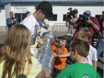  ?? ANDREW VAUGHAN PHOTOS/THE CANADIAN PRESS ?? Sidney Crosby began Monday by taking the Stanley Cup on a parade through Halifax, sharing it with children. The Pittsburgh Penguins captain also went to Rimouski, Que., where he played for the Oceanic junior team.