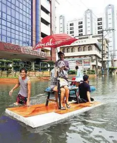  ??  ?? Water taxi A man pushes his improvised boat through floodwater­s in the Makati.
Reuters