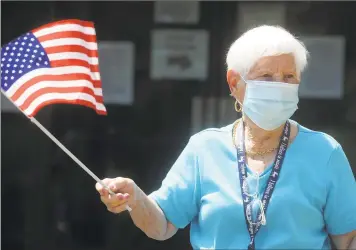  ?? Ned Gerard / Hearst Connecticu­t Media ?? Hollander House resident Theresa Giunta waves an American flag as she watches an Independen­ce Day drive-by parade in Bridgeport on Thursday. Volunteers drove through the Jewish Senior Services and Hollander House campus Thursday to help the residents celebrate the Fourth of July weekend.