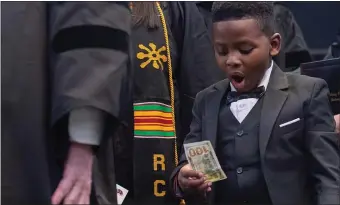  ?? ?? GREATEST GRAD GIFT: Wiley Cole-Shipman, 7, reacts after commenceme­nt speaker Robert Hale presents him with a $100 bill, as he accompanie­s his mom Tiara Dunbar across the stage.