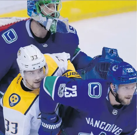  ?? THE CANADIAN PRESS/JONATHAN HAYWARD ?? Vancouver Canucks defenceman Alexander Edler tries to clear Nashville Predators left wing Viktor Arvidsson from in front of Vancouver Canucks goalie Anders Nilsson during second period NHL action in Vancouver, Wednesday.