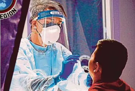  ?? EPA PIC ?? A health worker (left) conducting a swab test in Mandaluyon­g City, Metro Manila. Domestic travellers no longer need to undergo Covid-19 testing, unless the local government of a destinatio­n makes it a requiremen­t prior to travel.