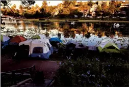  ?? LUIS SINCO/LOS ANGELES TIMES ?? A homeless encampment on the banks of Echo Park Lake in Los Angeles. Countless homeless people shelter in nooks and crannies in an urban landscape covered in graffiti and trash as the city struggles with reduced tax revenues and budgets.