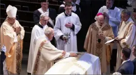  ?? Chris Machian/Omaha World-Herald via AP ?? Deacon Paul Cerio places a cross on Gutgsell’s casket during his funeral Monday at St. Cecilia Cathedral in Omaha, Neb.