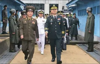  ?? South Korean Defense Ministry via Getty Images ?? South Korean Major Gen. Kim Do-gyun, right, is escorted by a North Korean officer after crossing the military demarcatio­n line for a meeting Thursday in Panmunjom, North Korea. Two Koreas began their first high-level military talks in more than 10...